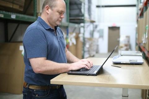 Warehouse operator using a laptop between shelves